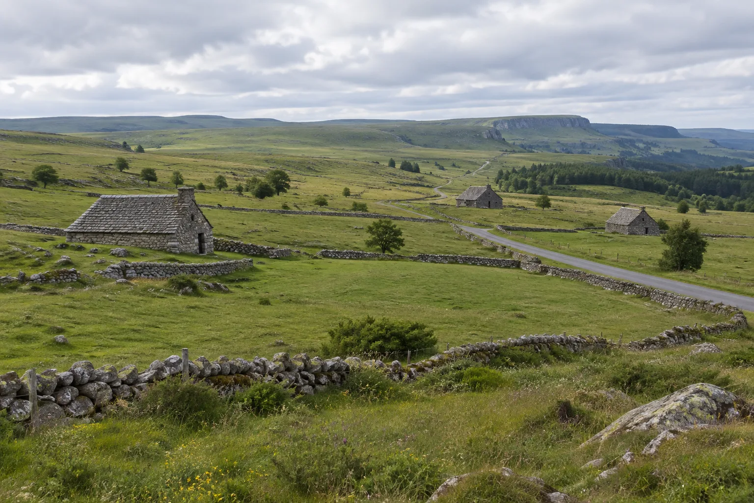 Pâturages et burons de pierre sur le plateau de l’Aubrac, sous un ciel changeant.